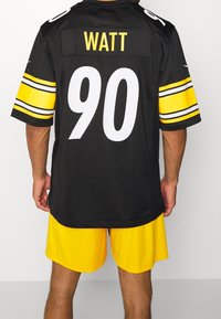 Maillot de football noir avec des rayures jaunes et blanches sur les manches, portant le nom "WATT" et le numéro "90" au dos ; associé à un short jaune.