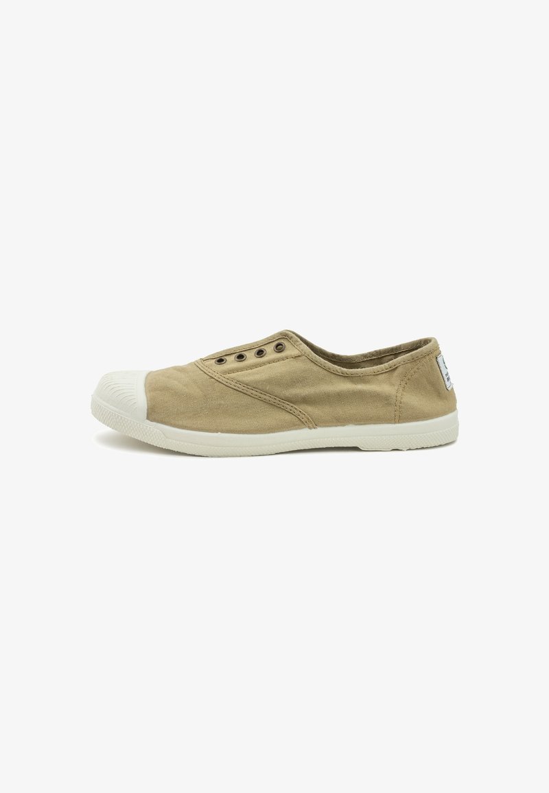 Chaussure slip-on en toile beige avec un embout en caoutchouc blanc, cinq œillets en métal et une semelle texturée. Pas de marquage visible.