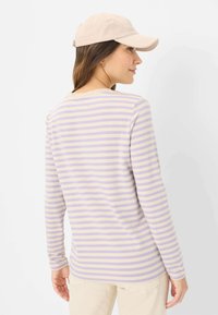 Gestreiftes Langarmshirt in Creme, Lavendel und Helllila. Mit rundem Halsausschnitt und weichem, glattem Stoff. Lässiges Design mit langen Ärmeln.