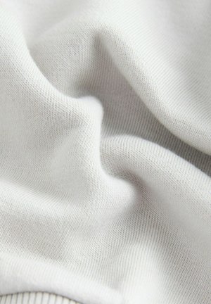 Tissu tricoté gris clair avec une texture lisse, présentant des côtes fines et régulières. Le matériau semble doux et extensible.