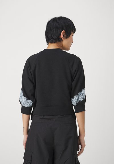 Felpa nera con maniche a tre quarti, caratterizzata da dettagli in pizzo azzurro chiaro sulle maniche e un colletto a costine. Vestibilità casual e design cropped.