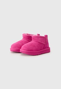 Botines de ante rosa con forro de pelaje, suela de goma plana y una correa de Velcro en la parte delantera para facilitar su uso.