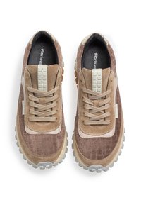 Des baskets en Suède marron avec des accents texturés, un revêtement en cuir beige, des lacets beiges et une semelle en caoutchouc robuste avec un relief prononcé.
