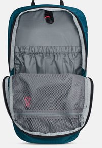 Τιρκουάζ σακίδιο πλάτης ανοιχτό που δείχνει τον μεγάλο κύριο χώρο με ελαστική θήκη και μπροστινή τσέπη με φερμουάρ από δίχτυ με κόκκινη ετικέτα τραβήγματος σε γκρι επένδυση.