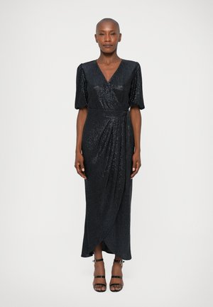 Rochie înfășurată neagră cu paiete, cu mâneci scurte tip puff, decolteu în V și fustă drapată. Modelul poartă sandale negre cu barete și stă în fața unui fundal alb.