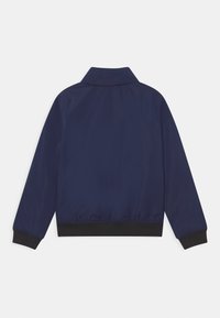 Námořnická modrá bomber bunda s hladkým povrchem, černými vroubkovanými manžetami a límcem. Má čistý, minimalistický design zadní části.