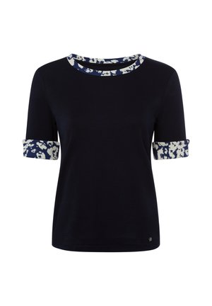 Haut bleu marine à manches courtes avec poignets repliés et bordure d'encolure présentant un motif abstrait blanc et bleu.