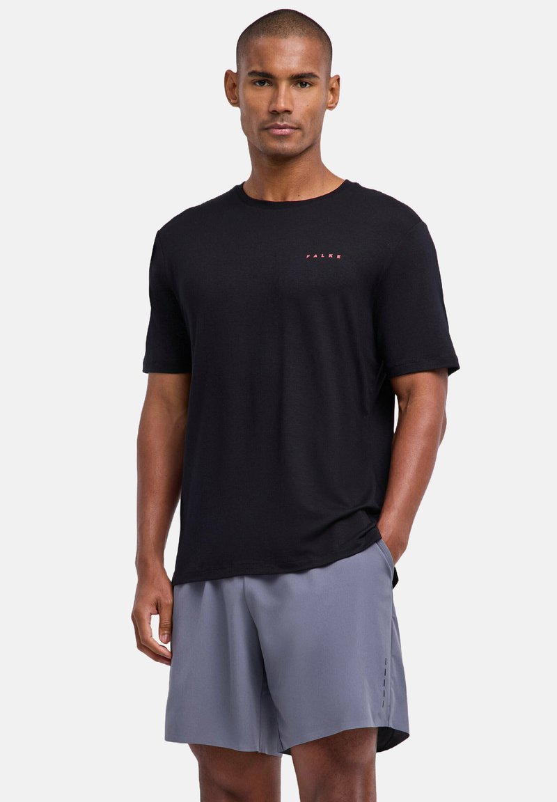 Chemise noire à manches courtes avec le logo rouge "FALKE", associée à un short gris avec de petites touches latérales et une coupe décontractée. Texture de tissu lisse.