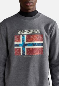 Sudadera gris con un gráfico de la bandera noruega, con acentos en azul y rojo, y el texto "NAPAPIJRI" y "ESTABLECIDO EN 1987".
