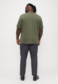 Cămașă verde măslinie cu mâneci scurte și pantaloni cargo gri închis. Pantalonii cargo au buzunare laterale și o croială confortabilă, fiind confecționa�ți dintr-un material fin.