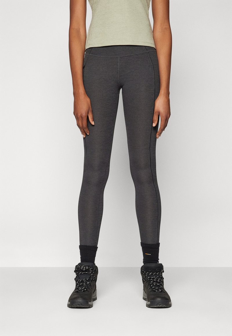Dark gray leggings with a smooth texture, featuring a high waistband and contrasting seam detail, paired with sturdy black hiking boots.