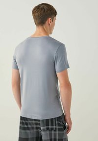 Harmaa lyhythihainen t-paita, jossa on pyöreä pääntie, sileä pinta ja slim fit -leikkaus, yhdistettynä mustavalkoisiin ruudullisiin shortseihin.