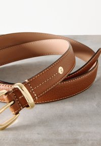 Tan leather belt with a textured finish, featuring a gold metal buckle and stitching accents. Includes a gold logo detail on the belt.
