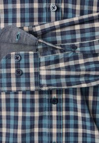 Blue and white checkered button-up shirt featuring a spread collar, contrasting pocket lining, and navy buttons with matching stitching.