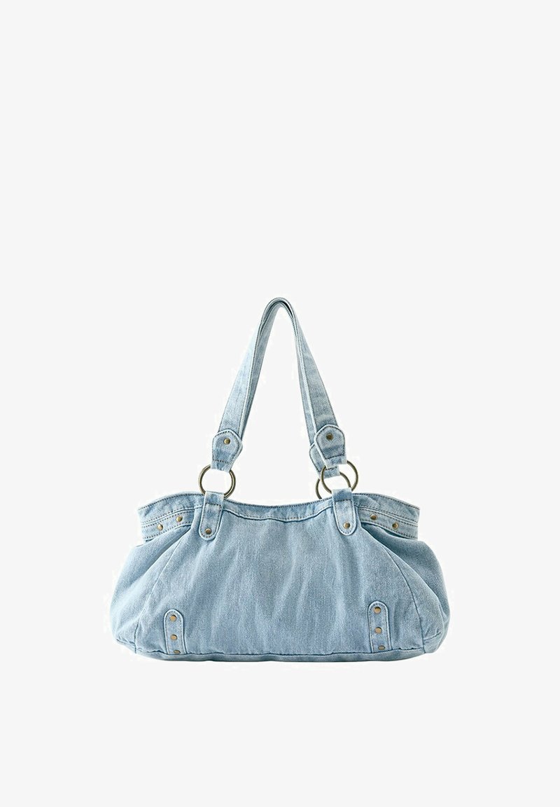 Sac à main en denim bleu clair avec deux bretelles attachées à des anneaux métalliques et des rivets décoratifs à l'avant et sur les côtés.