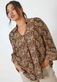 Brown and multicolored patterned blouse with a V-neck, long sleeves, and a relaxed fit, featuring a textured fabric and floral accents.