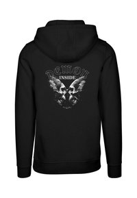 Sudadera negra con capucha que presenta un diseño gráfico de dos calaveras con alas y el texto "DEMON INSIDE" en una fuente gruesa. Textura de tela suave.
