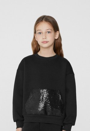 Schwarzer Pullover mit langen Ärmeln, rundem Ausschnitt und einer schimmernden, mit schwarzen Pailletten bedeckten Tasche auf der Vorderseite. Weicher Stoff.