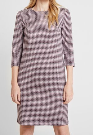 Robe à manches longues, longueur genoux, en motif pied-de-poule avec des couleurs rouge, blanc et marine. Fabriquée à partir d'un tissu texturé et ajusté.