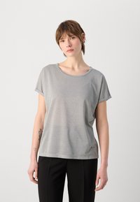 Zilveren T-shirt met korte mouwen en een ronde halslijn, met een subtiele glans. Zacht stof en een losse pasvorm, gecombineerd met zwarte broek.