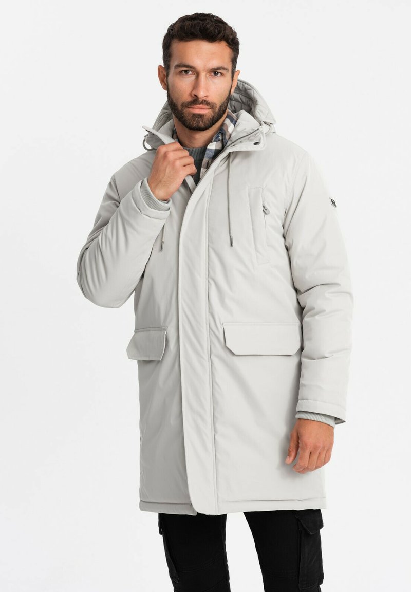 Ljusgrå knälång jacka med huva, med framfickor, en dragkedjeförsedd bröstficka och justerbara dragsnören på huvan.