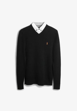 Maglione nero a maglia con scollo a V, abbinato a una camicia bianca con colletto e bottoni neri e un colletto interno a righe. Piccolo logo arancione di aragosta sul petto.