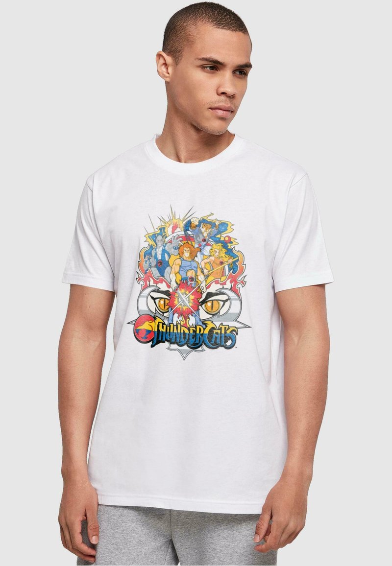 Valge puuvillane T-särk, millel on värvikas graafika ThunderCats'i tegelastest, julgete joontega ja keskel logo. Lühikesed varrukad, ümar kaelus.