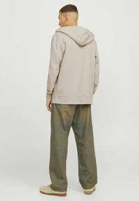 Hanorac bej cu o glugă mare, manșete și tiv din material ribbed. Purtați cu pantaloni verzi pal, într-o croială lejeră, și încălțăminte bej. Design simplu.