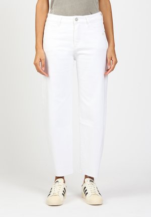 White denim jeans with a straight-leg design, featuring a frayed hem. Paired with white and black sneakers. Textured fabric.