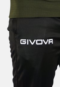Pantaloni sportivi neri con logo ricamato bianco "GIVOVA" sul lato sinistro. Vita a coste verde oliva, tessuto dalla superficie liscia.