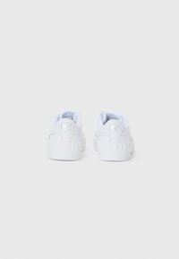 Pair of white Puma sneakers with thick soles, viewed from the back, showing the Puma logo on the heel tabs.
