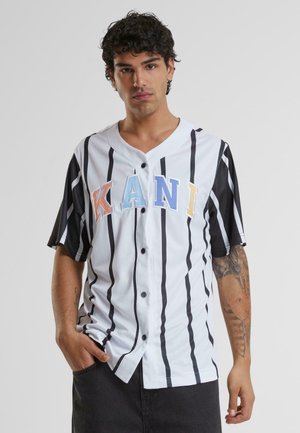 White and black striped short-sleeve shirt with colorful "KANI" lettering, buttoned front, and a relaxed fit. Features a V-neck.