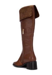 Bota de cuero marrón hasta la rodilla con un puño de ante doblado, cremallera lateral y un tacón grueso. Textura suave con acabado mate.
