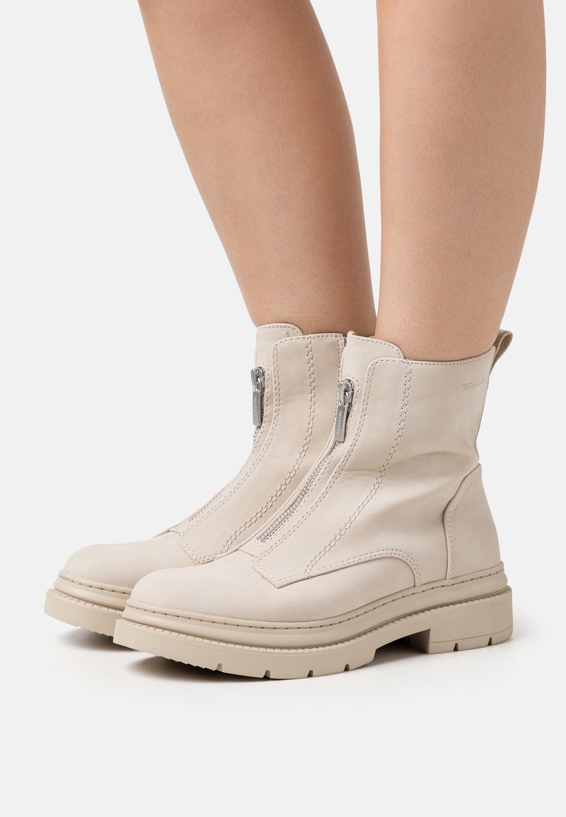 Bottes de cheville beiges en daim doux, présentant des zips latéraux doubles, une semelle épaisse texturée et des accents de couture sur la tige.