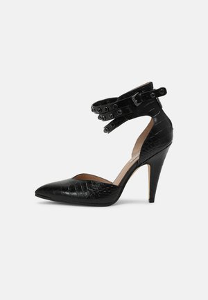 Zapato negro de tacón alto con punta afilada, textura de cocodrilo, correa en el tobillo con tachuelas decorativas y un elegante tacón de aguja.
