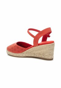 Sandalias cuña coral con puntera abierta, parte superior perforada y plataforma de yute trenzado. Presenta una doble correa cruzada en el tobillo.