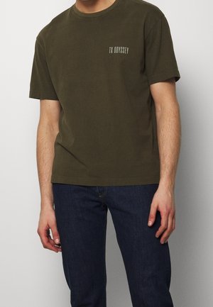 Olijfgroen katoenen T-shirt met korte mouwen, ronde hals en kleine witte tekst "TX ODYSSEY" op de borst. Soepele textuur, casual pasvorm.