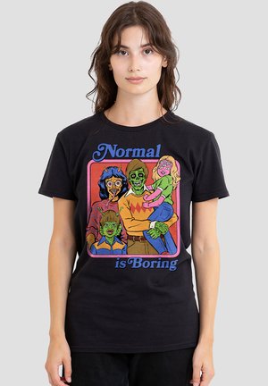 Young woman wearing black T-shirt with colorful cartoon of a family of monsters and the text "Normal is Boring" on front.