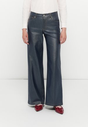 Donkerdenim wijde broek met een hoge taille. Bevat traditionele zakken en contrasterende stiksels. Gecombineerd met rode schoenen.