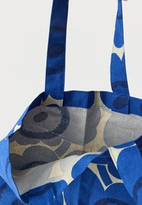 Τσάντα tote από ύφασμα με μπλε σχέδια, διαθέτει φαρδιές μπλε λαβές και εσωτερικό σε μπεζ χρώμα με λουλουδάτα σχέδια σε γκρι και μπλε.