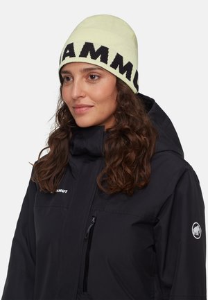 Gebreide beanie in lichtgroen met gedurfde zwarte letters. Draag de beanie met een zwarte jas met een ritszak en een logopatch.