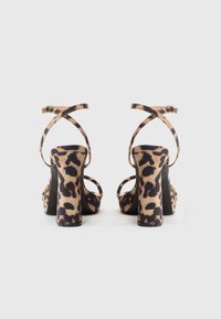 Pantofi cu toc platformă cu imprimeu de leopard, cu vârf pătrat, curele încrucișate la glezne și toc gros. Fabricate dintr-un material moale, cu o finisare netedă.