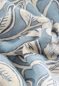 Soft fabric with light blue and white floral patterns, showing detailed texture and gentle folds.
