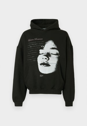 Černá mikina s kapucí z bavlny s volným střihem; má bílý motiv obličeje a nápis "Lost in Romance" vytištěný růžovou barvou.