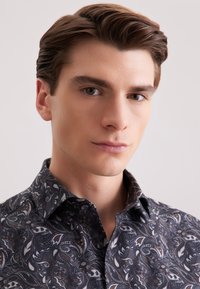 Camicia a fantasia paisley scura con una texture morbida, caratterizzata da un colletto button-down e sfumature sottili di blu e marrone in tutto il design.