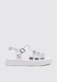 Sandalias de plataforma blancas con correas metálicas y un acento texturizado en plata. Hebilla ajustable en el tobillo. Suela blanca texturizada.