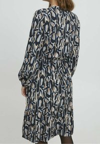 Robe à imprimé floral avec des manches longues, un ourlet en couches et une taille élastique. Les couleurs incluent du bleu foncé, du beige et du bleu clair avec une texture lisse.