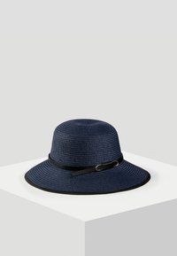 Granatowy słomkowy kapelusz z szerokim rondem; posiada czarną opaskę z metalowym zapięciem i teksturowanym wykończeniem.