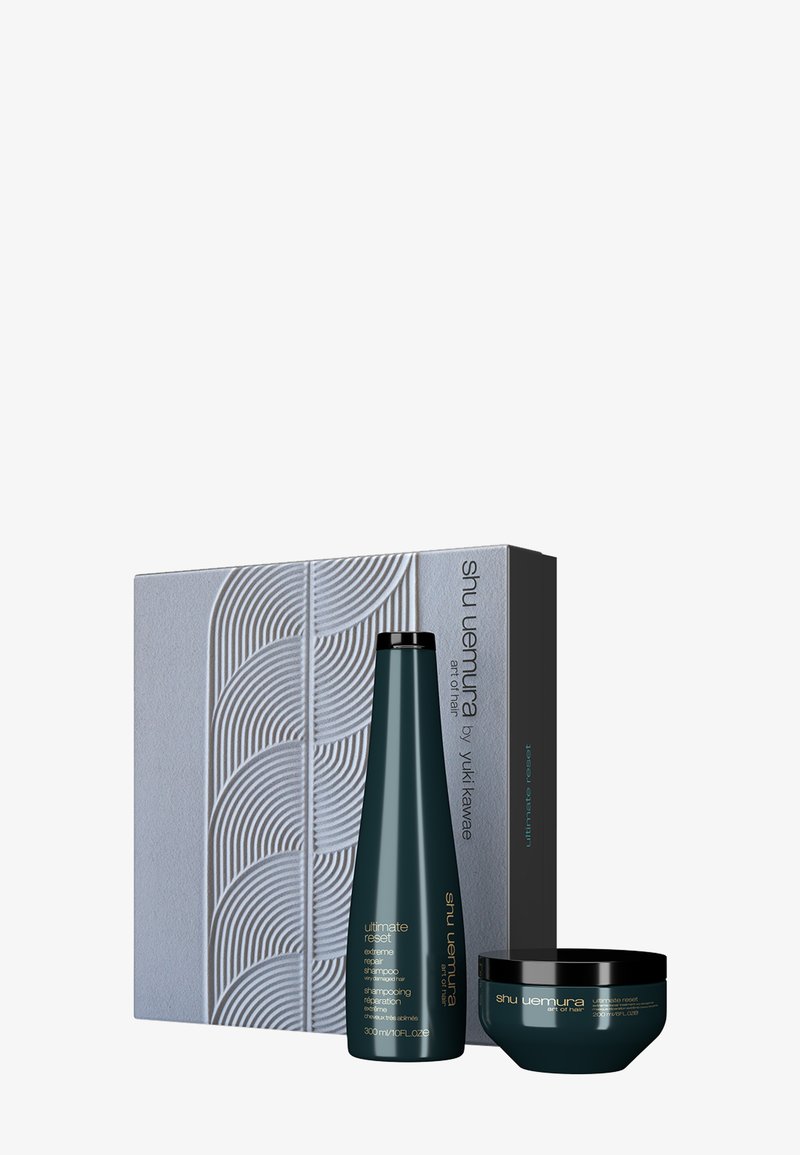 Shu Uemura Ultimate Reset haarverzorgingsset; bevat een teal shampoo-fles en pot, met textuur grijze verpakking met golfpatronen.