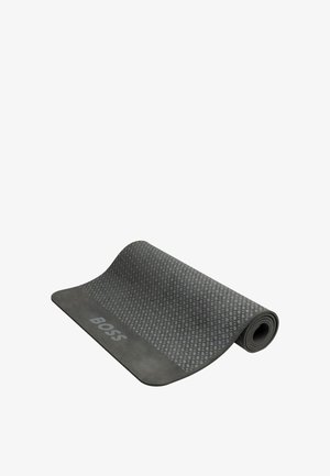 Delvis hoprullad mörkgrå yogamatta med diamantmönster och "BOSS"-märke i ena änden.